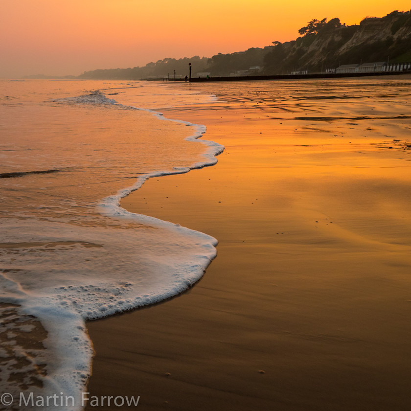 Branksome-Sunset 
 Sandy shore at sunset with gentle waves breaking on wet sand 
 Keywords: Bournemouth, Branksome, beach, breaking, foam, orange, ripples, sand, sea, shore, sun, sunset, water, waves, wet, winter