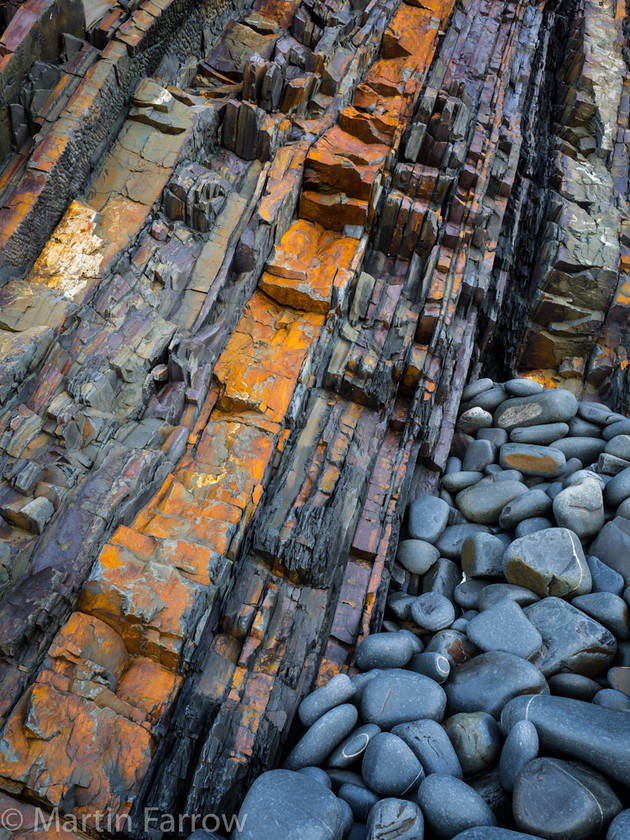 Strata-And-Pebbles 
 Vertical strata and pebbles on shore 
 Keywords: Devon, Hartland, North Devon,shore,rocks,pebbles,strata,rust,vertical,coast