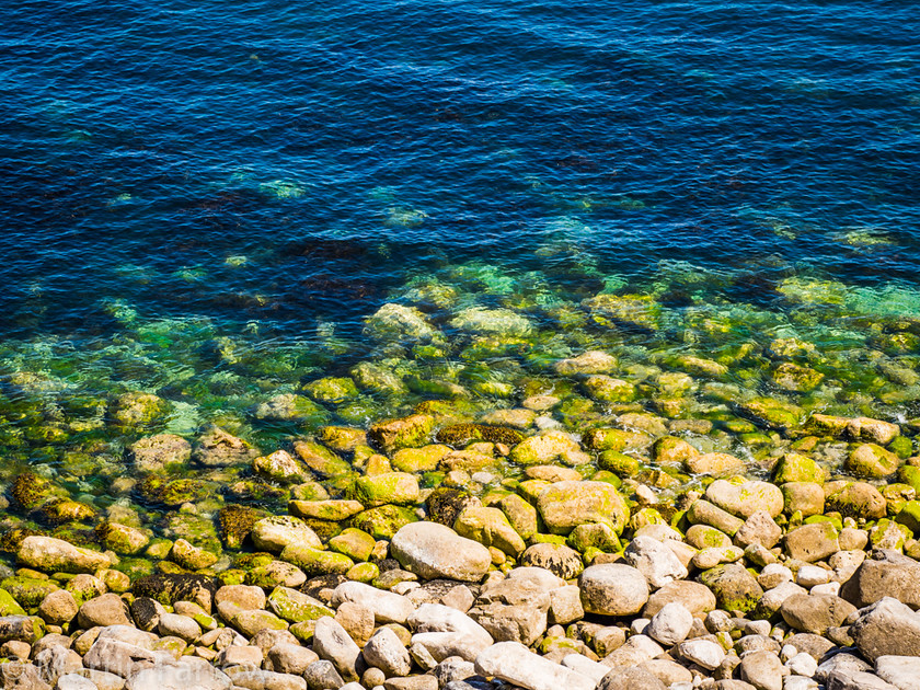 Blue-Water 
 Stony shore with calm blue water lapping the rocks 
 Keywords: Dorset, Portland, beach, blue, calm, landscape, ocean, pebbles, rocks, sea, shore, stones, summer, view, water