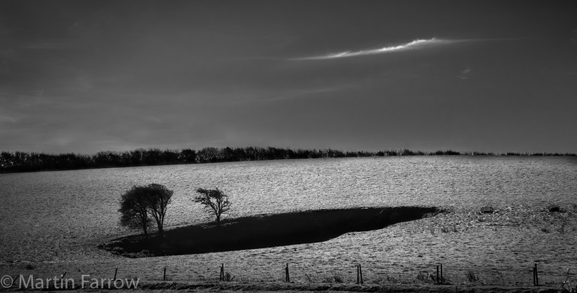 Passing-Cloud 
 Small cloud reflecting the shape of shady hollow in large field 
 Keywords: Isle of Wight, autumn, cloud, contrast, countryside, dark, field, light, monochrome, shadow, trees