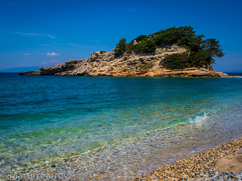 Inviting 
 Small island in blue sea 
 Keywords: Greece, Samos, clear,blue,sea,ocean,water,wave,island,trees,rock,ripple,blue,shore,beach