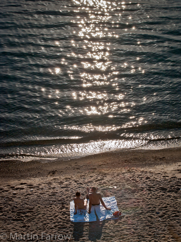 Watching-The-Sun-Set 
 Couple on beach watching setting sun 
 Keywords: Chora, Greece, Mykonos,couple,two,shore,beach,towel,waves,sea,ocean,water,ripples,reflection,sun,setting